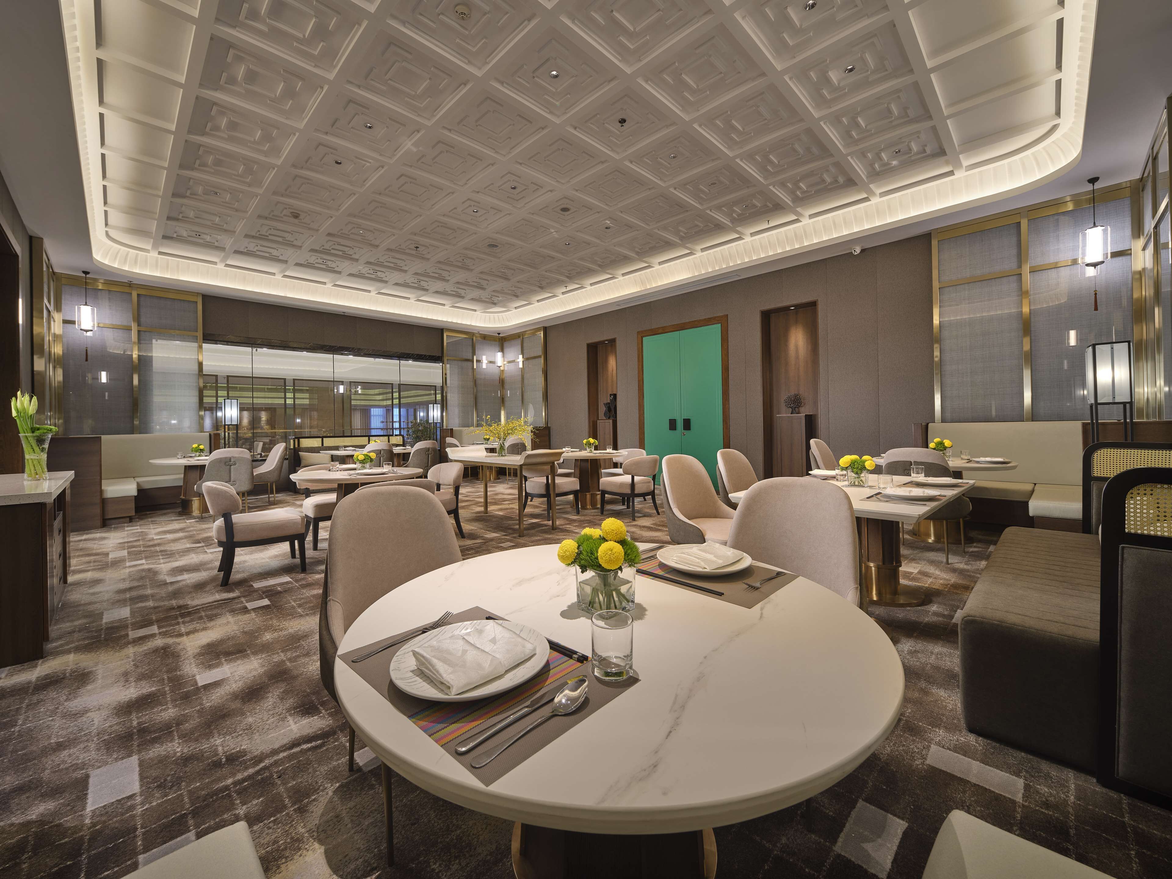 Un salón de conferencias de hotel con mesas redondas, sillas y una puerta verde.