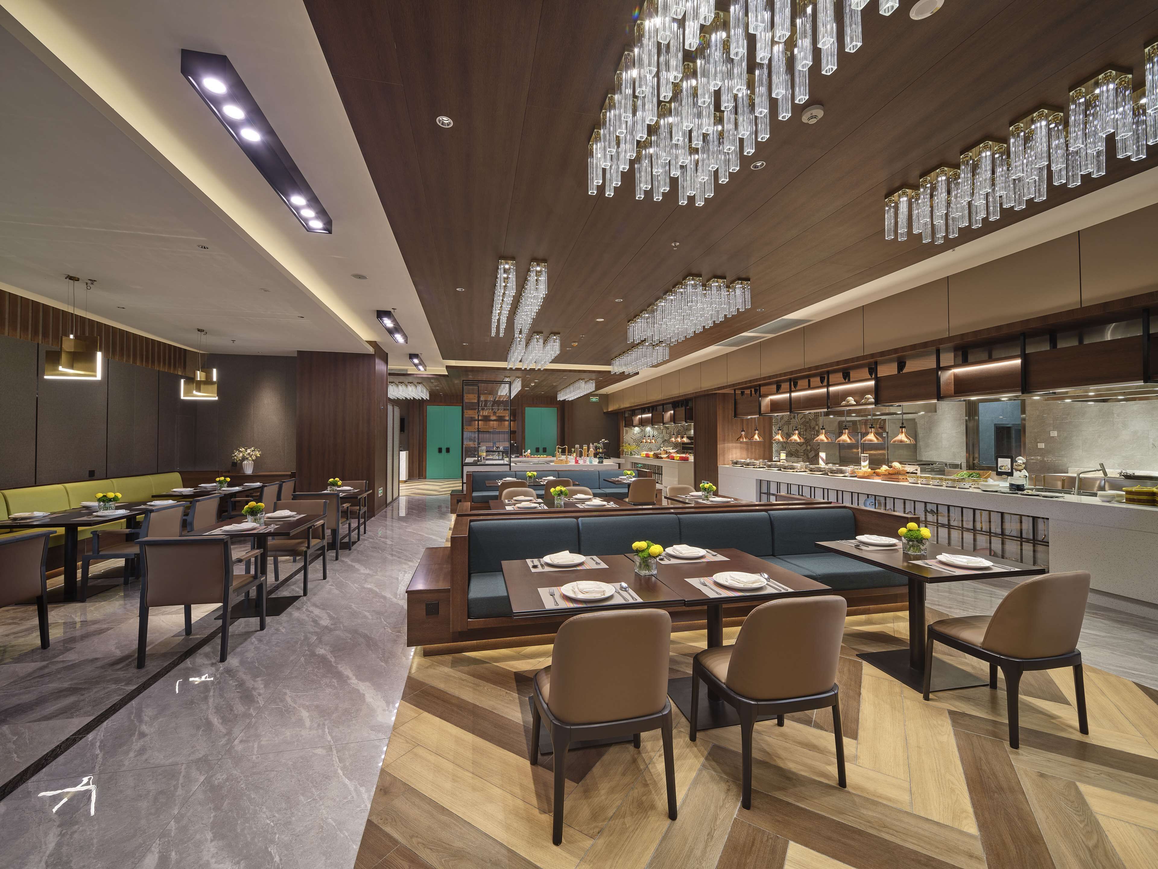 A modern restaurant interior with high-end furnishings, a central seating area, and a visible kitchen.