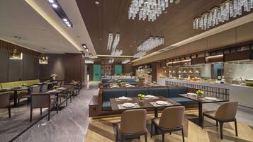 A modern restaurant interior with high-end furnishings, a central seating area, and a visible kitchen.