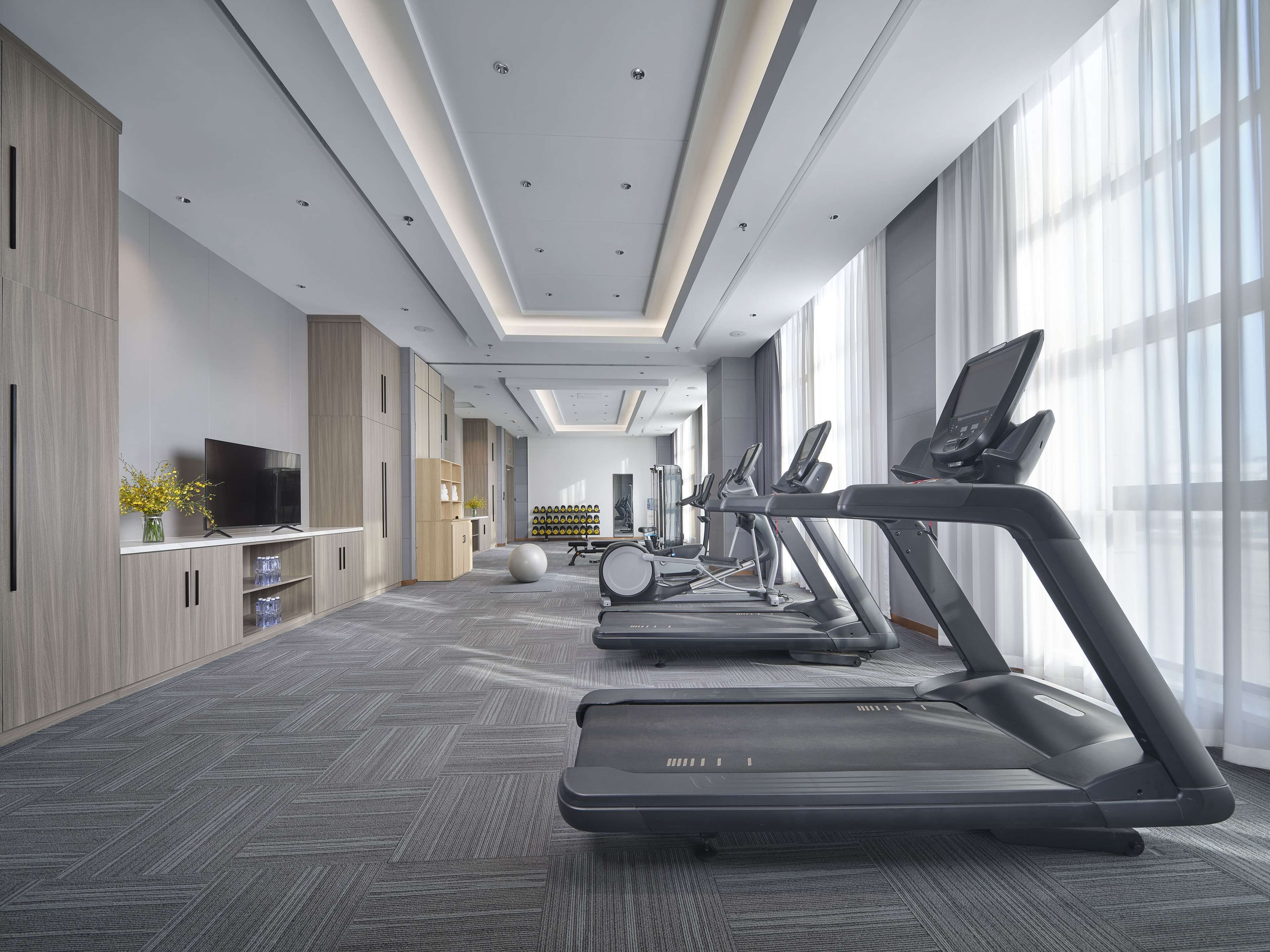 A modern fitness room with treadmills, a television, and exercise equipment.