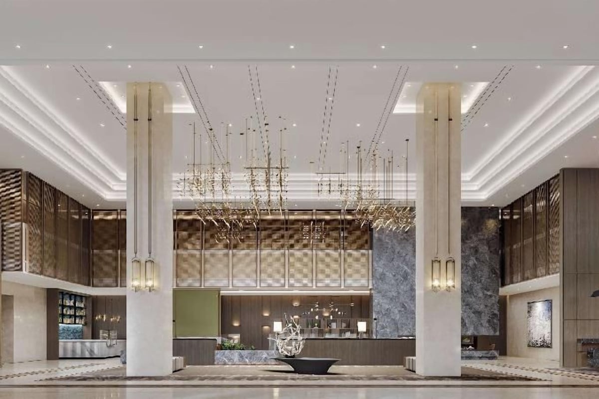 Um hall amplo com uma recepção central, tetos altos e luminárias modernas.