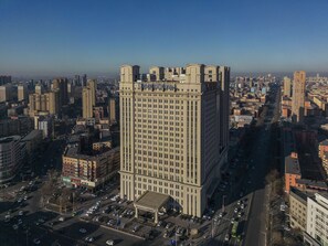 A high-rise building with a prominent central tower and a smaller building attached to its base. - Doubletree By Hilton Anshan (Anshan)