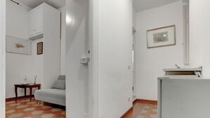 A room with a sofa, a small table with a lamp, a cabinet, and a refrigerator. - Charming Colosseum - HOME AND MORE (Roma)