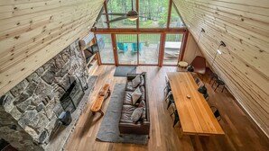 A spacious loft with a high ceiling, stone walls, and a large glass door leading to an outdoor deck.