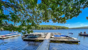 A dock with boats, a pier, and a lake surrounded by trees.