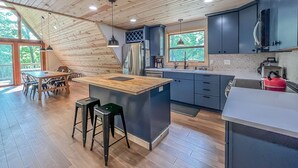 A modern kitchen with a wooden ceiling, a large island, and a view of the outdoors.