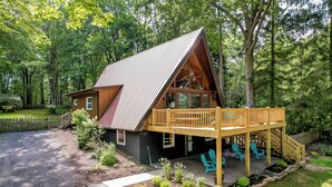 A cabin with a deck, surrounded by a forest.