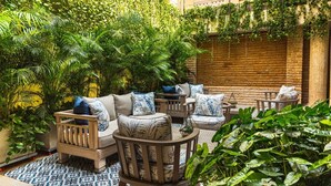 A cozy outdoor seating area with wooden furniture and lush greenery. - CC-3 HABITACION DOBLE EN GETSEMANI (Cartagena)