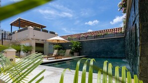 A pool area with a pergola, lounge chairs, and a stone wall. - CC-3 HABITACION DOBLE EN GETSEMANI (Cartagena)