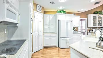 Une cuisine avec des meubles blancs, un four à micro-ondes, une cuisinière et un réfrigérateur.