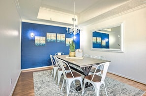 Comedor con una pared azul decorativa, una araña y cuadros enmarcados.