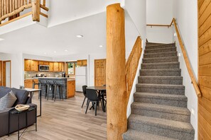 A modern interior with a wooden staircase, a kitchen area, and a dining space.