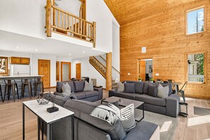 A spacious living area with a high ceiling, wooden beams, a staircase, and a large window. - Spacious and Peaceful 5 Mins to Ski Area/Main St (Breckenridge)