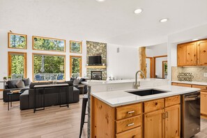 A modern kitchen with a stone backsplash, wooden cabinets, and a large island with a sink. - Spacious and Peaceful 5 Mins to Ski Area/Main St (Breckenridge)