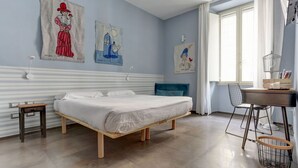 A bedroom with a bed, a small table, a chair, and a window with curtains. - CAPO D'AFRICA 30 COLOSSEO - HOME AND MORE (Roma)