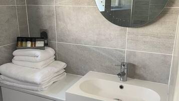 A bathroom with a round mirror, a sink, and a toilet.