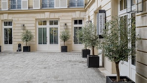 Un patio con área de recepción, varios pisos con balcones y plantas en macetas.