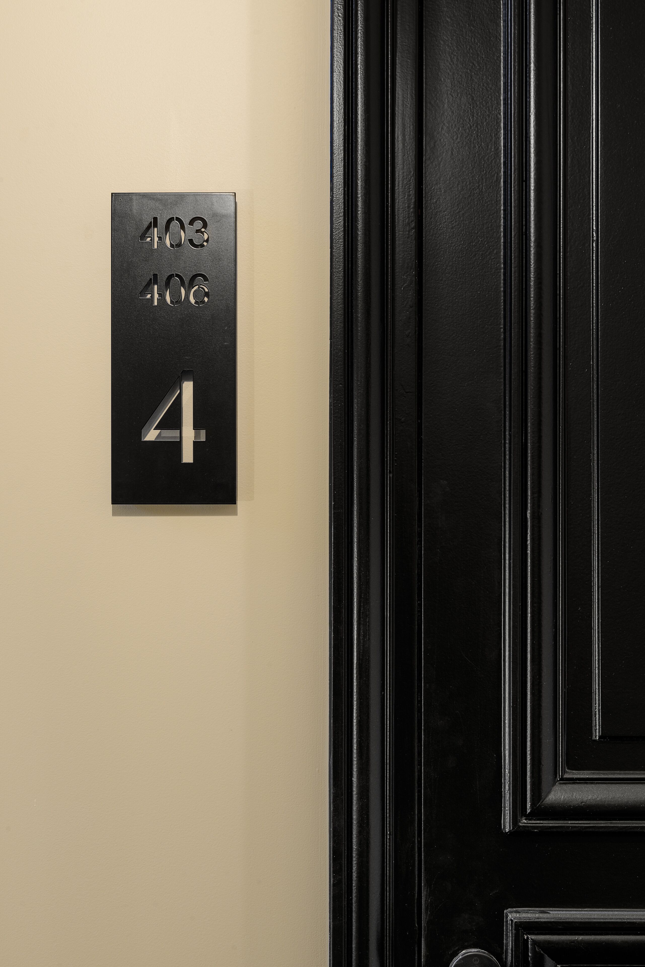 A black door with a black sign displaying room numbers 403 and 406.