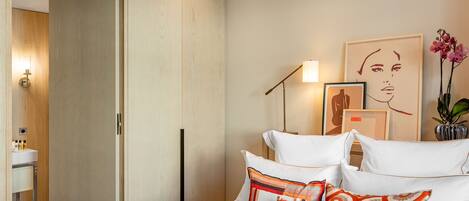 A modern bedroom with a bed, pillows, a bedside table, and a nightstand.