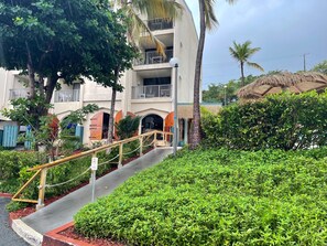 Un immeuble à plusieurs étages, doté de balcons, d’un escalier et d’une végétation luxuriante.