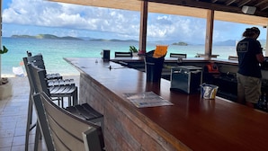 Un espace bar avec vue sur la mer, un plafond en bois et des sièges.