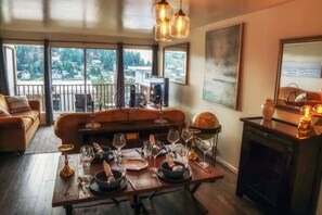 A dining area with a table set for a meal, a sofa, and a fireplace. - The Mariner in Meydenbauer Bay  29 Nights (Bellevue)