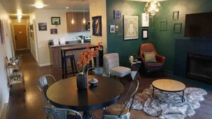 A modern living room with a dining area, a fireplace, and a kitchen in the background. - Stylish 2 Bedroom Capitol Hill Apartment (Seattle)