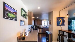 A modern kitchen with a central island, stainless steel appliances, and a dining area with bar stools. - Stylish 2 Bedroom Capitol Hill Apartment (Seattle)