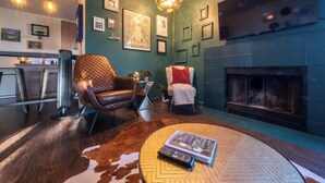 A cozy living room with a fireplace, leather chairs, and a round coffee table with a book and remote control. - Stylish 2 Bedroom Capitol Hill Apartment (Seattle)