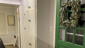 A hallway with a green door, white walls, and a patterned rug. - Cute, cozy, updated cottage just steps from gorgeous Houghton Lake (Prudenville)