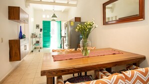 A dining area with a wooden table, chairs, a vase with flowers, and a mirror on the wall. - Casitas Miramar Puerto Vallarta Malecón (Puerto Vallarta)
