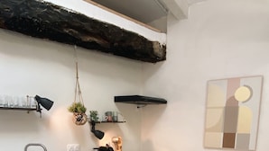 Una cocina moderna con armarios blancos, encimera de madera, horno empotrado y una planta colgante.