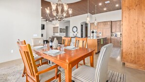 Un comedor moderno con una mesa de madera, sillas a rayas y una lámpara de araña.