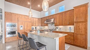 Una cocina moderna con armarios de madera, electrodomésticos de acero inoxidable y una isla central con taburetes de bar.