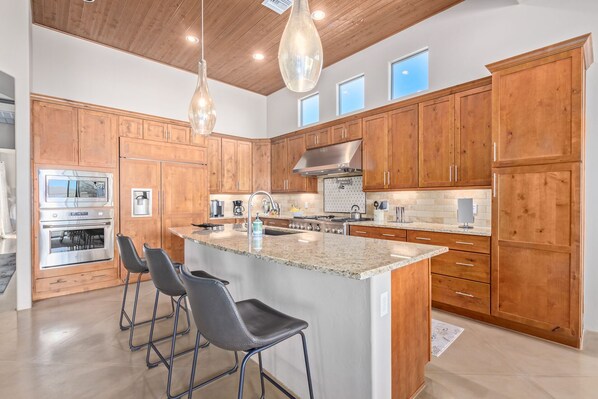 A modern kitchen with wooden cabinets, stainless steel appliances, and a central island with bar stools.