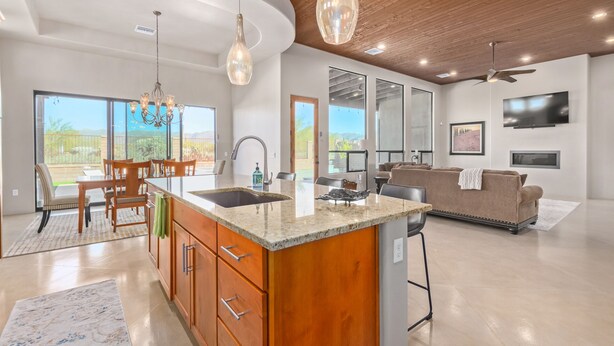 Una cocina amplia con una isla grande, elegantes lámparas colgantes y vistas al exterior.