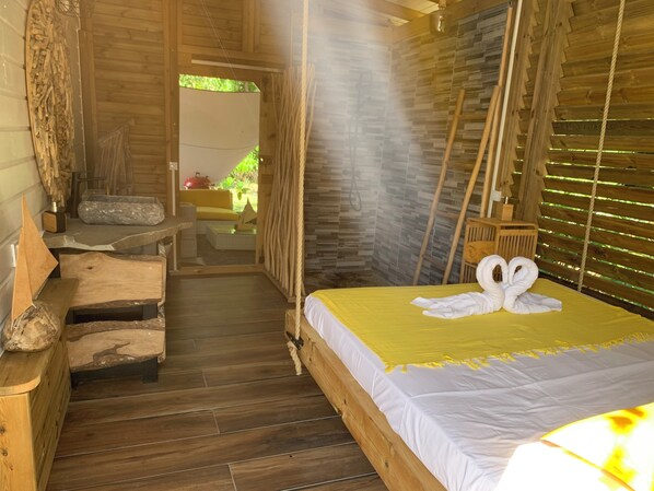 A wooden cabin room with a bed, a bench, and a small table.