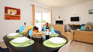 A dining area with a table set for two, a bottle of wine, and a fruit basket. - Heatable pool & BBQ retreat in Carvoeiro (Carvoeiro)