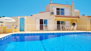 A two-story house with a swimming pool, a balcony, and a covered outdoor seating area. - Heatable pool & BBQ retreat in Carvoeiro (Carvoeiro)