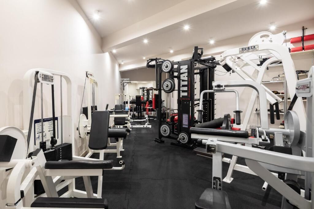 Un gimnasio con diferentes máquinas de ejercicio, incluyendo un rack para sentadillas y bancos de pesas.
