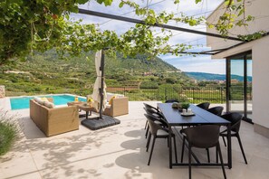 An outdoor patio with a pool, wicker furniture, and a dining table with chairs.