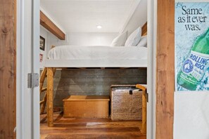 A bunk bed room with a wooden ladder, a small wooden chest, and a poster on the wall. - Monterey Log Lair With Pool Table - Slope Views (Big Bear Lake)