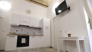 Une cuisine avec des meubles blancs, un four noir, un plan de travail en bois et une table blanche.