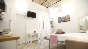 Une chambre d’hôtel avec un lit, un bureau, une télévision et un tableau au mur.