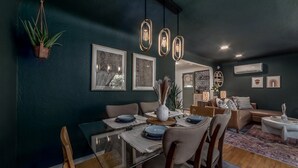 Uma área de refeições moderna com mesa de vidro, cadeiras e luminárias pendentes.