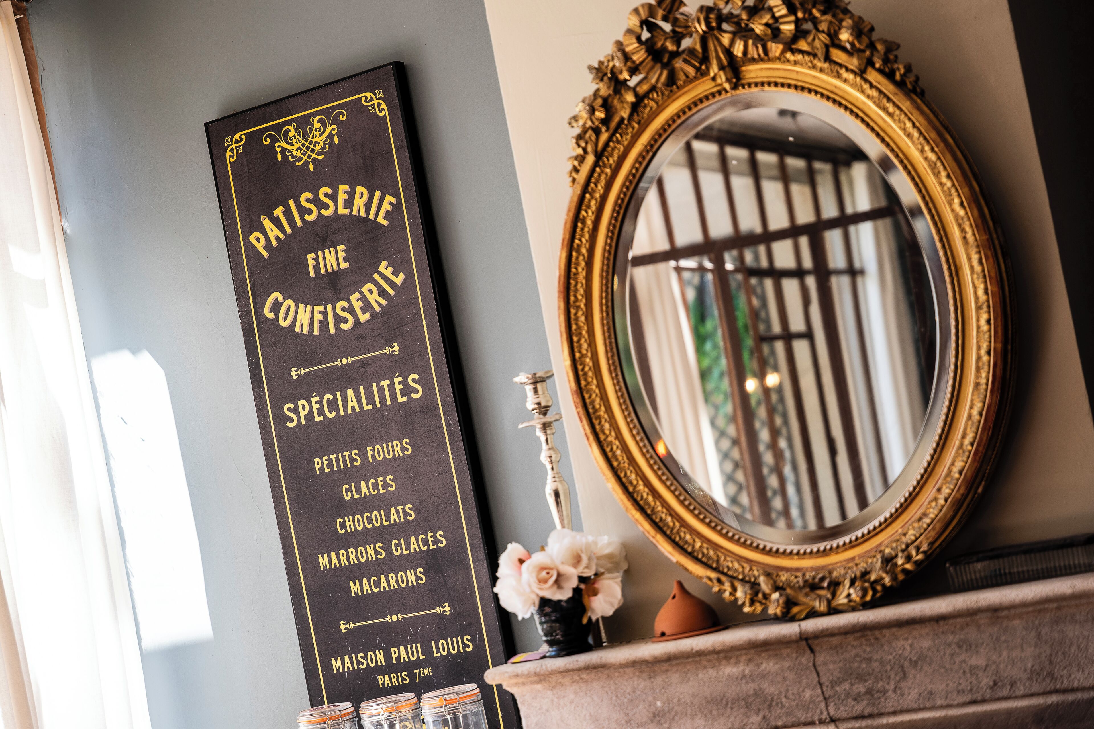 A black menu board with gold lettering listing specialties like petits fours and macarons.