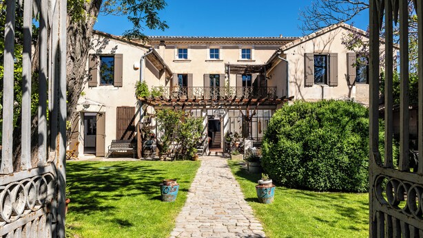 A courtyard with a stone pathway leading to a building with multiple windows and a covered entrance.