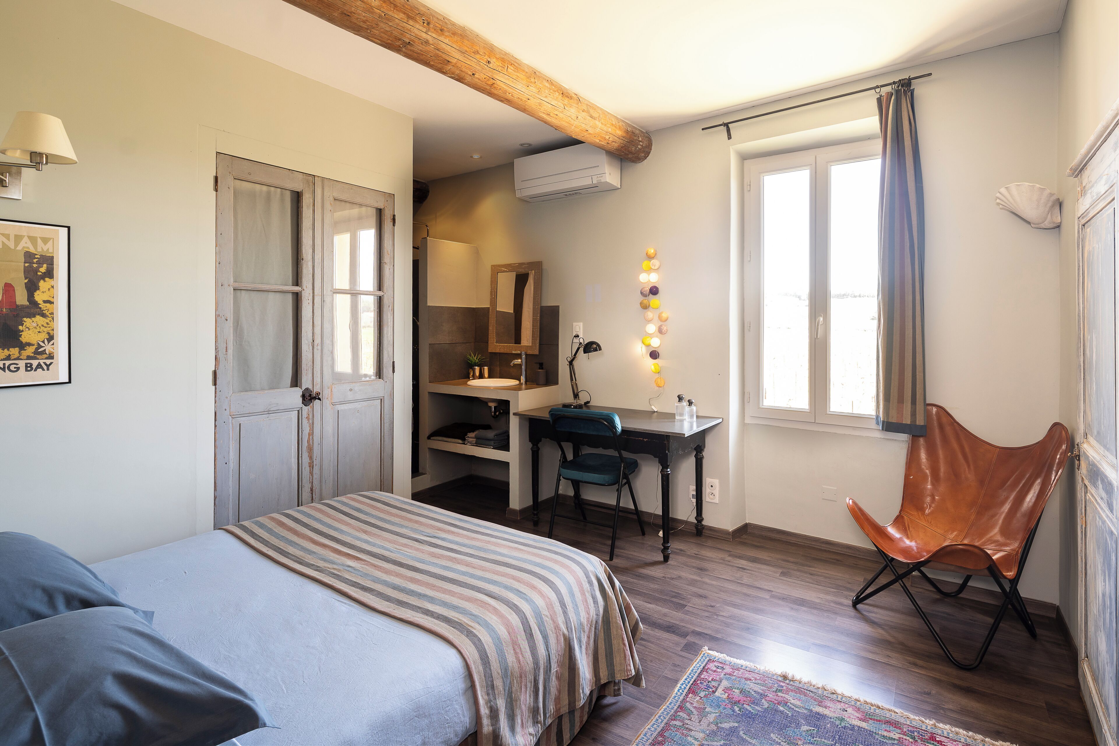 A bedroom with a bed, a desk, a chair, and a window with curtains.