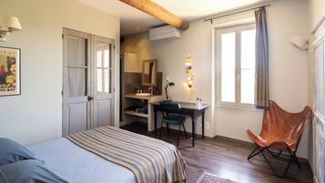 A bedroom with a bed, a desk, a chair, and a window with curtains.