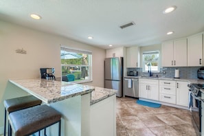 A modern kitchen with white cabinets, a stainless steel refrigerator, and a granite countertop.